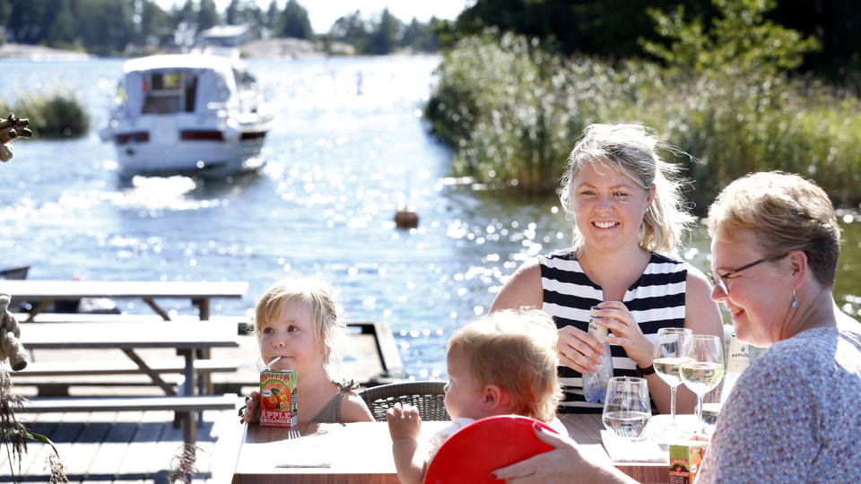 En grupp människor som sitter och äter på en restaurang i hamnen.