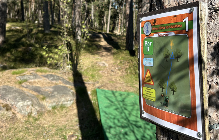 En skylt sitter uppsatt på ett träd i skogen.