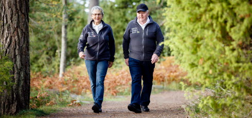 Äldre man och kvinna är ute och promenerar i ett motionsspår